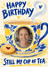 A blue and yellow floral teacup with lemon motifs holds an oval photo frame, with curling steam, a heart biscuit and blue brush wording on cream.