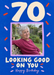 A large cream seventy and lilac portrait frame sit on cobalt blue, surrounded by pink and red confetti and rounded hand-lettered wording.